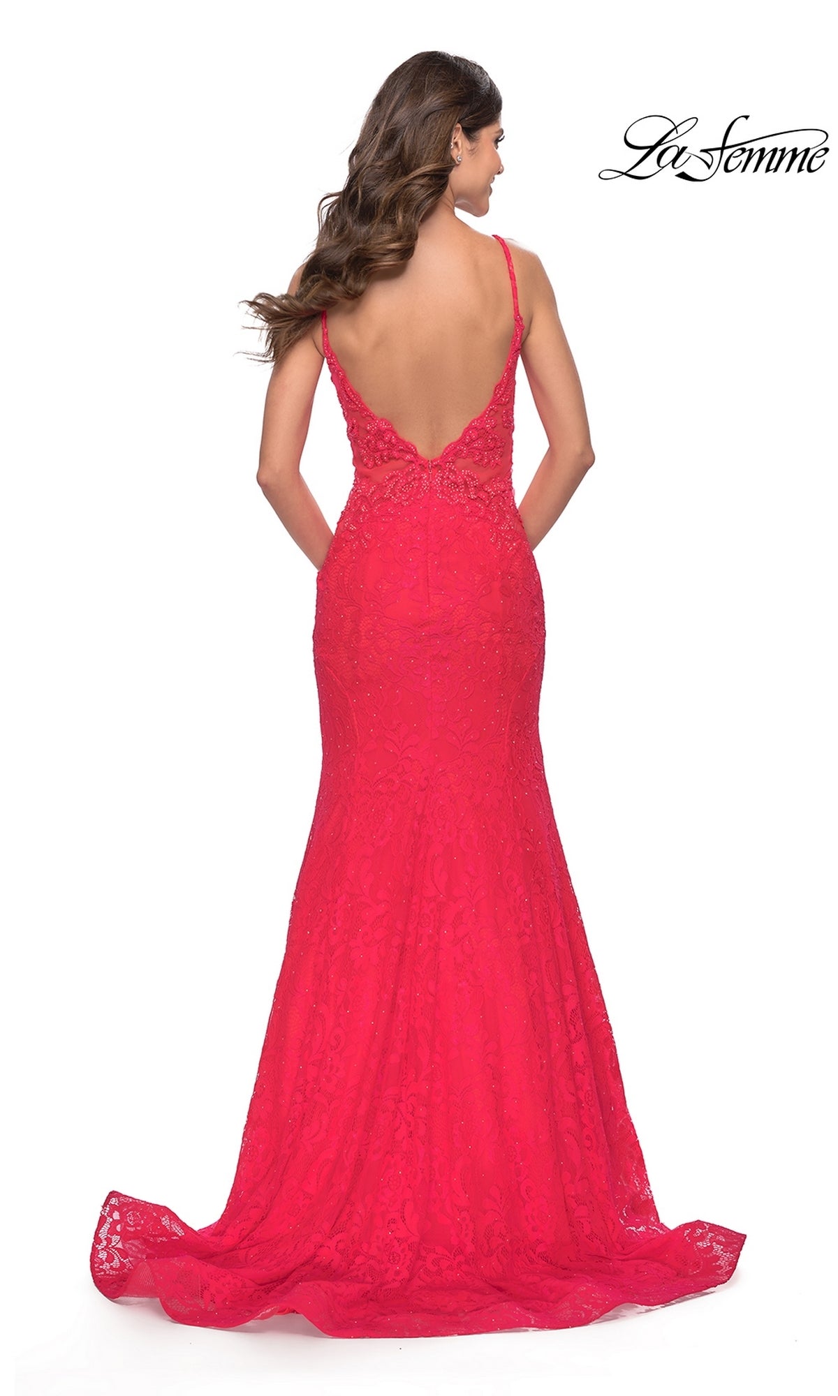 A woman stands with her back to the camera, wearing the La Femme 31512—a bright red long lace mermaid prom dress with thin straps and a low back.